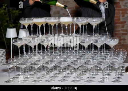 A pyramid of champagne glasses is filled with two bottles during a party Stock Photo