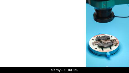 Microscope examining electronic circuit board on blue surface with clear focus on components and surrounding equipment for detailed analysis Stock Photo