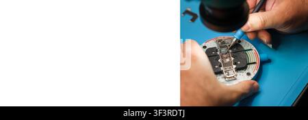 Close-up of hands repairing electronic circuit board with precision tools on a blue work surface in a technical workshop environment Stock Photo