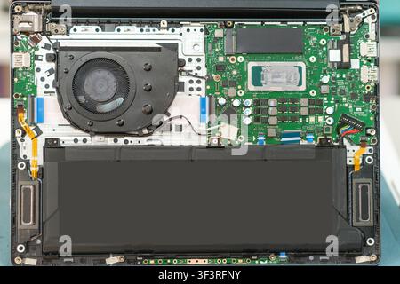 Laptop motherboard and internal components displayed, including fan, battery, and circuit board, showcasing intricate electronic design and layout Stock Photo