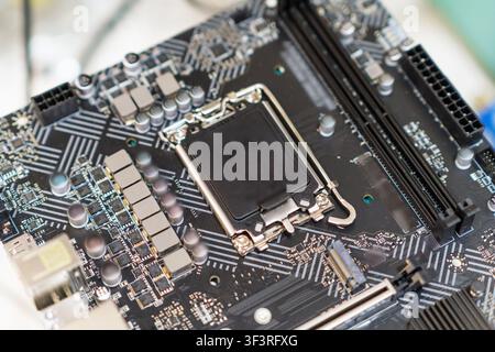 Close-up view of a computer motherboard showcasing intricate circuitry, CPU socket, and various electronic components on a workbench Stock Photo