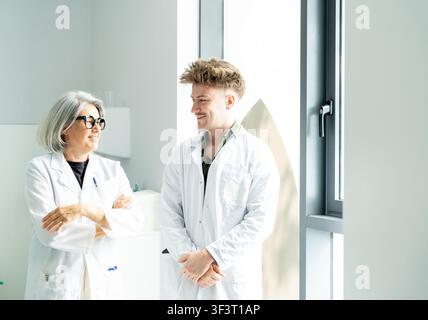 Two diverse medical professionals in lab coats having a friendly conversation Stock Photo