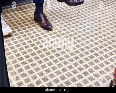 A close-up view of a floor completely covered with a repeating grid pattern of QR codes printed on beige tiles. The geometric black-and-white Stock Photo