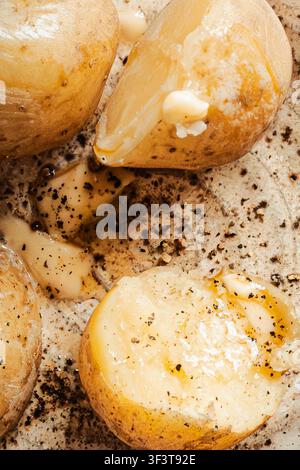 Fresh organic skin-on new potatoes with golden butter melting over warm potatoes with freshly ground black pepper. Earthy, farm-to-table aesthetic. Stock Photo