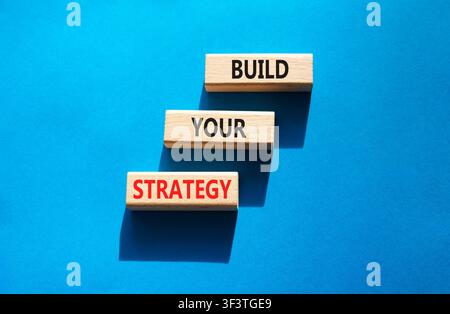 Build your strategy symbol. Concept words build your strategy on wooden blocks arranged as steps. Strategic planning concept. Blue background. Copy sp Stock Photo