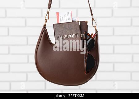 Brown leather shoulder bag with passport, boarding pass, and sunglasses for international travel Stock Photo