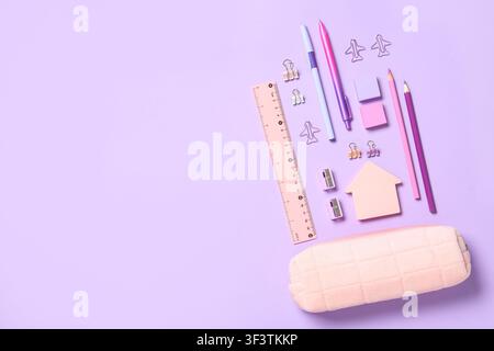 School supplies and stationery items, including pens, pencils, ruler, and pencil case, on a light purple background, the collection includes pens, pen Stock Photo
