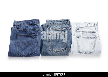 Three folded denim jeans in varying shades of blue, from dark to light, isolated on a white background Stock Photo
