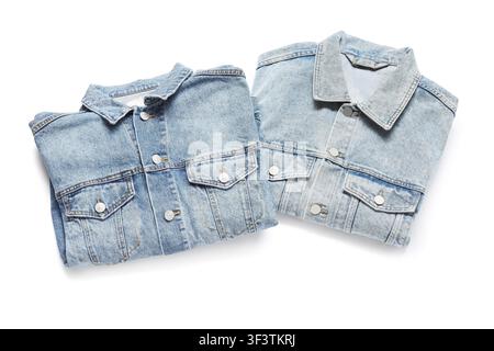 Two folded light blue denim jackets with metal buttons and chest pockets, casual fashion apparel isolated on a white background Stock Photo