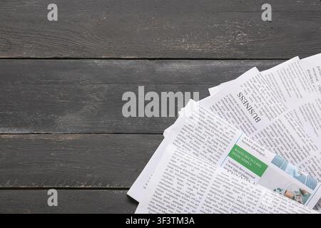 Stack of newspapers with business and finance news on a dark wooden table, top view with copy space, Stack of newspapers with business and finance sec Stock Photo