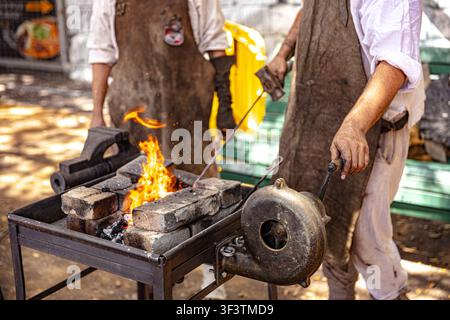 A blacksmith demonstrates traditional 18th-century metalworking and forging techniques at a living history camp in Alameda del Duque de Santa Elena, Stock Photo