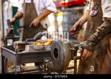 A blacksmith demonstrates traditional 18th-century metalworking and forging techniques at a living history camp in Alameda del Duque de Santa Elena, Stock Photo