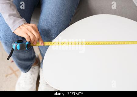 Mature woman measuring coffee table at home, top view Stock Photo