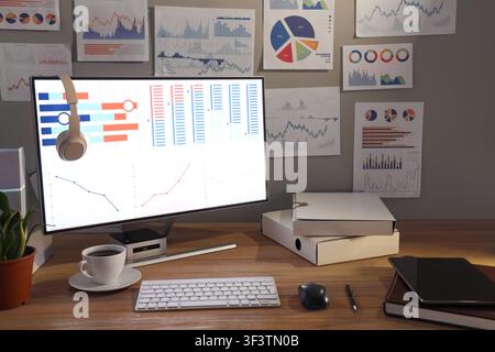 Data scientists workplace with computer and diagrams in dark office Stock Photo