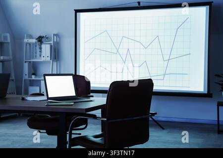 Interior of data scientists office with workplace, laptop and diagrams on projector screen Stock Photo