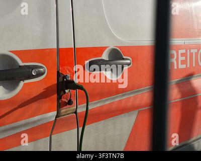 Close-up detail of an emergency vehicle's side doors featuring orange and silver/white livery. Two black door handles are visible, with the left Stock Photo