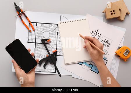 Architectural design process with blueprints, smartphone, and construction tools on a gray background, top view Stock Photo