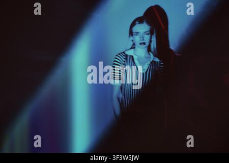 A mysterious figure stands out in a striped fashion under a surreal neon glow. The long exposure creates an ethereal feel, enhancing the aura of myste Stock Photo