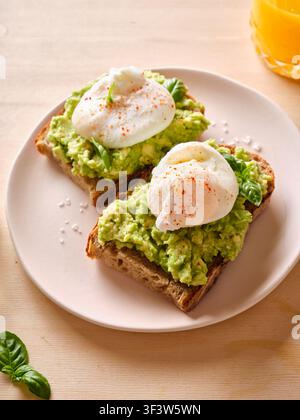 A delicious brunch featuring creamy avocado spread on hearty toast, topped with perfectly poached eggs. A healthy and satisfying breakfast dish. Stock Photo