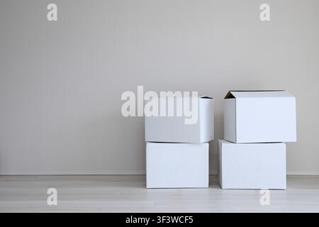 White cardboard boxes stacked against a wall in a bright room Stock Photo