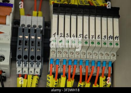Industrial electrical control panel with electronic relay modules, terminal blocks, and status LED indicators in a manufacturing machine switchboard. Stock Photo