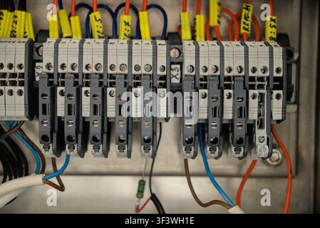 Close-up of industrial electrical terminal blocks with wire markers and numbered cables in a control cabinet. Stock Photo