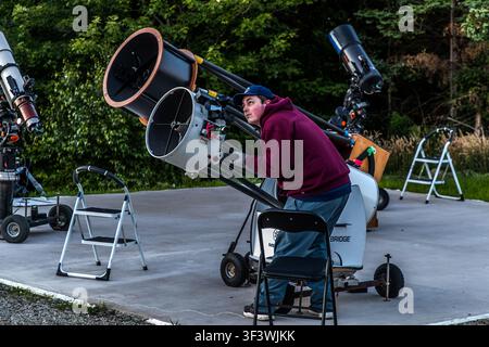 A young man is adjusting a telescope on the forecourt of the Deep Sky Eye Observatory on Frotten Road near Tusket, Nova Scotia. The observatory, which has been in operation since 2015, is situated in North America’s first Starlight-certified destination. Argyle Municipal, Nova Scotia, Canada Stock Photo