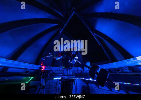 A computer-controlled telescope stands beneath the open dome of the Deep Sky Eye Observatory on Frotten Road in the Municipality of Argyle, Nova Scotia, Canada. Blue lighting is used during night-time operations to protect visitors’ night vision whilst the dome segments are open for observation. Argyle Municipal, Nova Scotia, Canada Stock Photo