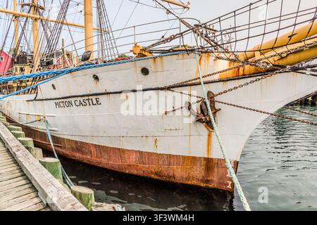 The bow of the Picton Castle, with its anchor and rusty anchor chains, is moored at the quay in Lunenburg, Nova Scotia. Built in 1928, the barque has served as a training ship for sailing courses lasting several months since the 1990s; its unofficial home port is Lunenburg. Lunenburg, Nova Scotia, Canada Stock Photo