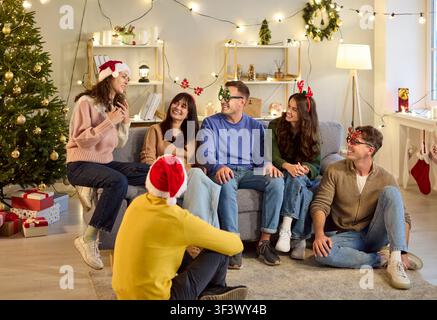 Group of young friends laughing and talking during home Christmas party together Stock Photo
