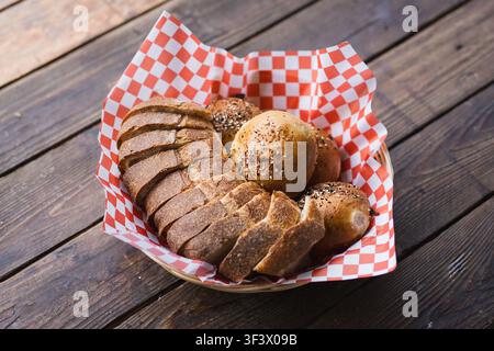 Artisan Sourdough Bread and Seeded Rolls Served in Basket on Wooden Table Stock Photo