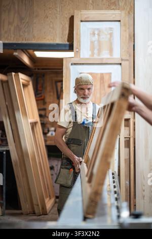 Professional man carpenter working in restoration workshop on vintage wooden door reconstruction Stock Photo