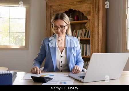 Businesswoman working with documents, reviewing financial report displaying charts Stock Photo