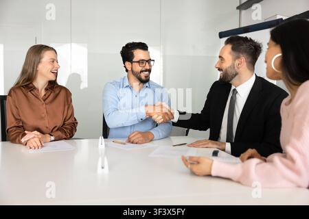 Multiethnic business partners shaking hands during meeting in corporate office Stock Photo