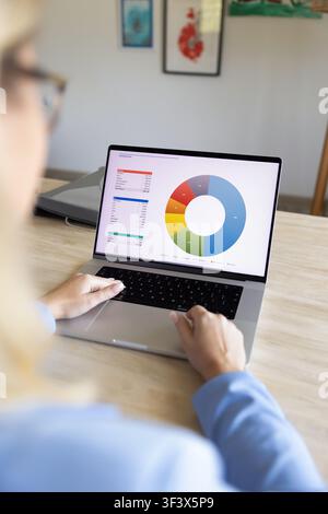 Businesswoman analyzing financial data with chart on laptop, closeup Stock Photo