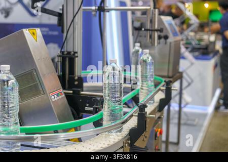 automated production line with plastic water bottles. A machine vision system with a bright light inspects one bottle for quality control in a factory Stock Photo