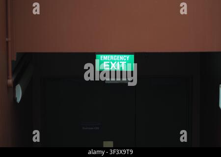 Emergency exit sign over dark door in hall Stock Photo