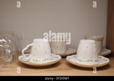 Cups and saucers on a wooden shelf in a kitchen Stock Photo