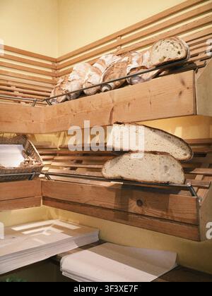 Pforzheim, Germany July 26, 2026. Vertical view of freshly baked sourdough bread loaves and sliced bread displayed on wooden slatted shelves inside a Stock Photo