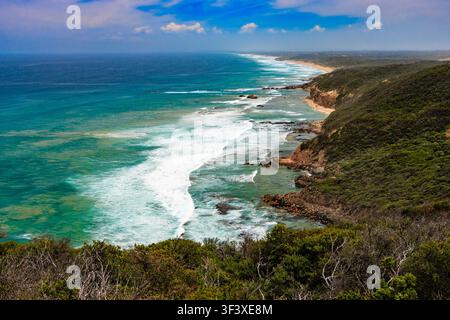 Turquoise ocean waves breaking along the rugged coastline at Fingal Beach on the Mornington Peninsula, Victoria, Australia, with cliffs, dense vegetat Stock Photo