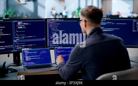 Young Male Software Engineer Coding Secure Algorithms On Laptop In Office. Stock Photo