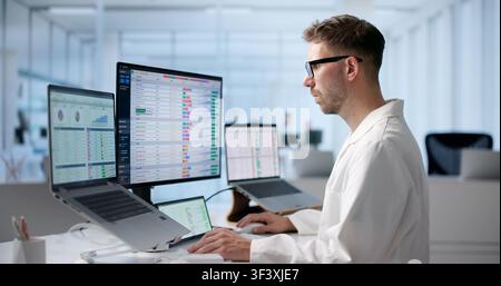 Young Man Reviews Medical Billing Codes On Laptop For Accurate Healthcare Invoices. Stock Photo