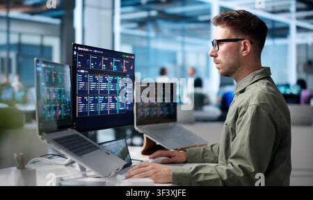 Young IT Specialist Monitors Real-time Network Performance Using Advanced Computer Tools. Stock Photo