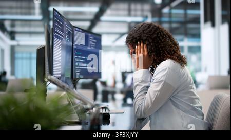 Tired African Female Coder Struggles With Headache While Debugging Code Late. Stock Photo