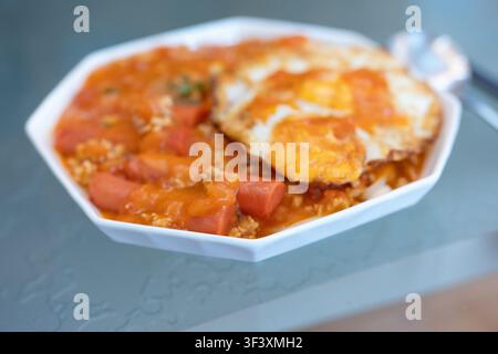 Vietnamese-style fried rice with tomato sauce, sliced sausage, and sunny-side-up egg served in a Stock Photo