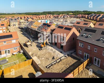 Aerial view above affordable semi detached new build homes under construction with eco friendly heating systems including rooftop solar panels on a bu Stock Photo