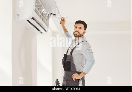 Portrait of electrician with screwdriver looking at camera maintaining air conditioner Stock Photo