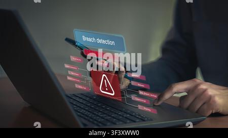 Cybersecurity breach detection concept with alert warning icon and technical digital graphics on laptop. Stock Photo