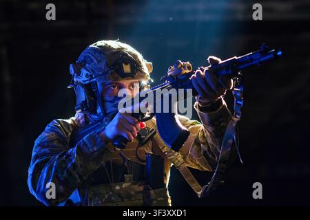Soldier in Tactical Gear Aiming an Assault Rifle With Night Vision Under Dramatic Lighting Stock Photo