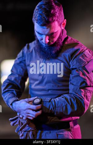 Tactical Soldier Checking Watch At Night In Military Jacket With Gloves And Neon Lighting Stock Photo